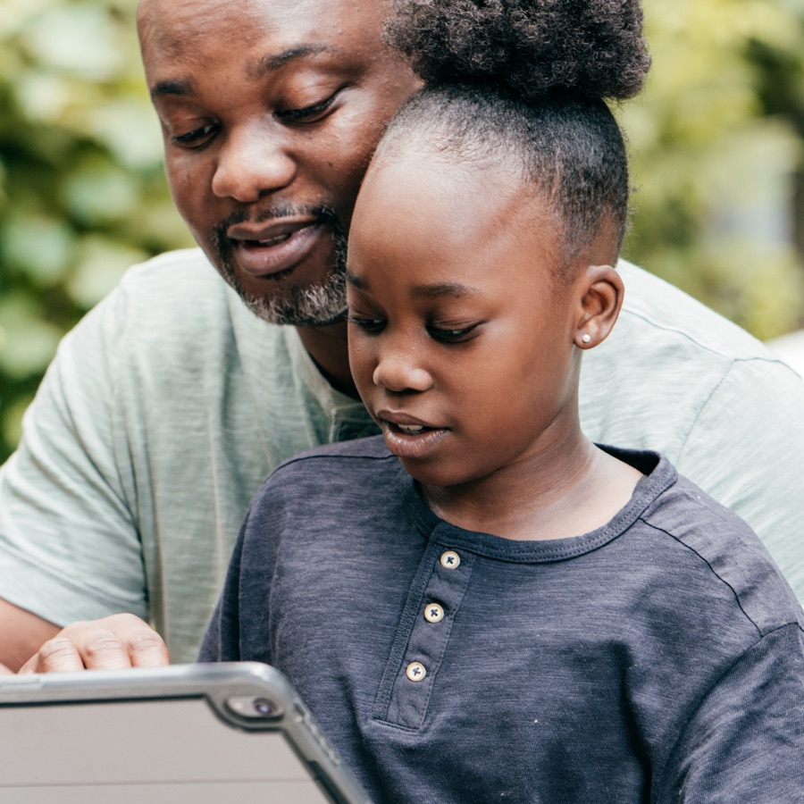 A parent helping a child learn on a tablet at home