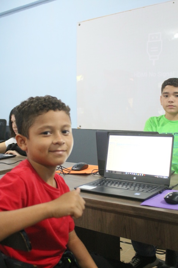 A student giving a thumbs up in the Kids-Teck computer lab