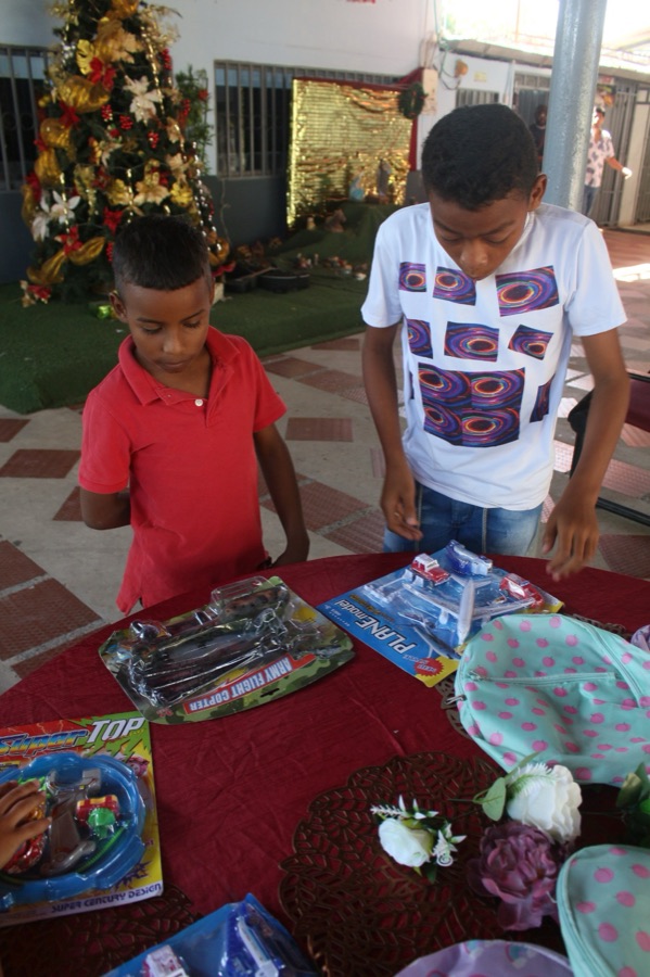 Two boys examining toy gifts by a Christmas tree